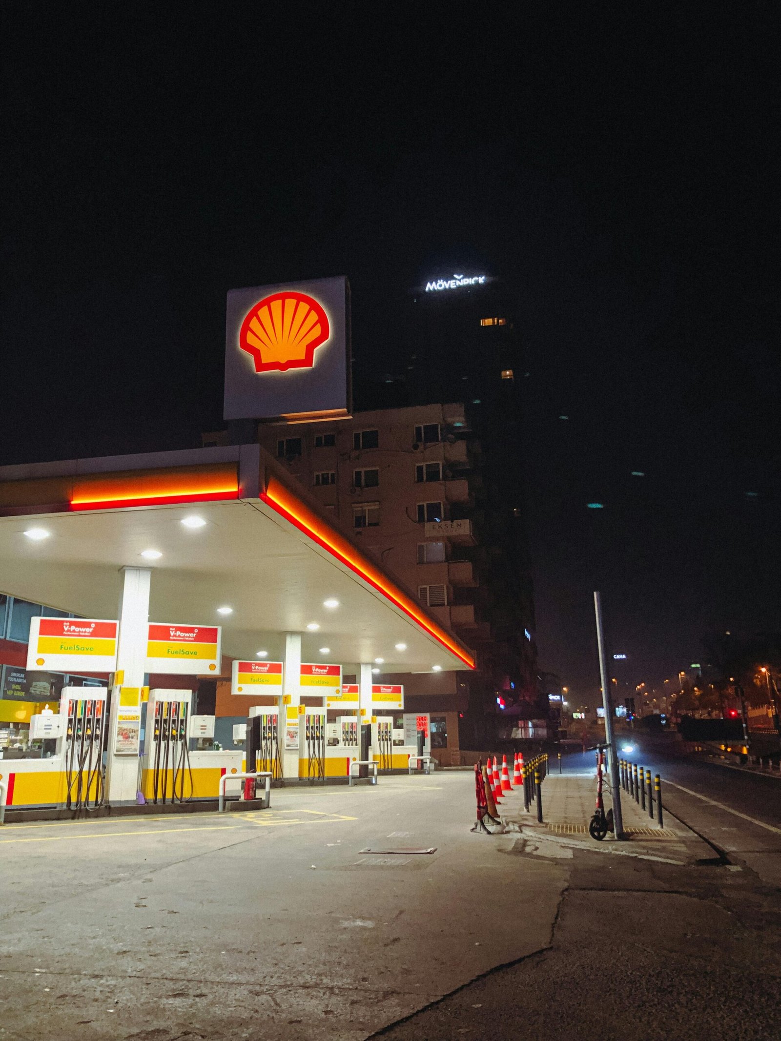 Station-service de nuit avec plusieurs pompes à carburant éclairées, illustrant la distribution de carburants dont l'éthanol E85 en milieu urbain